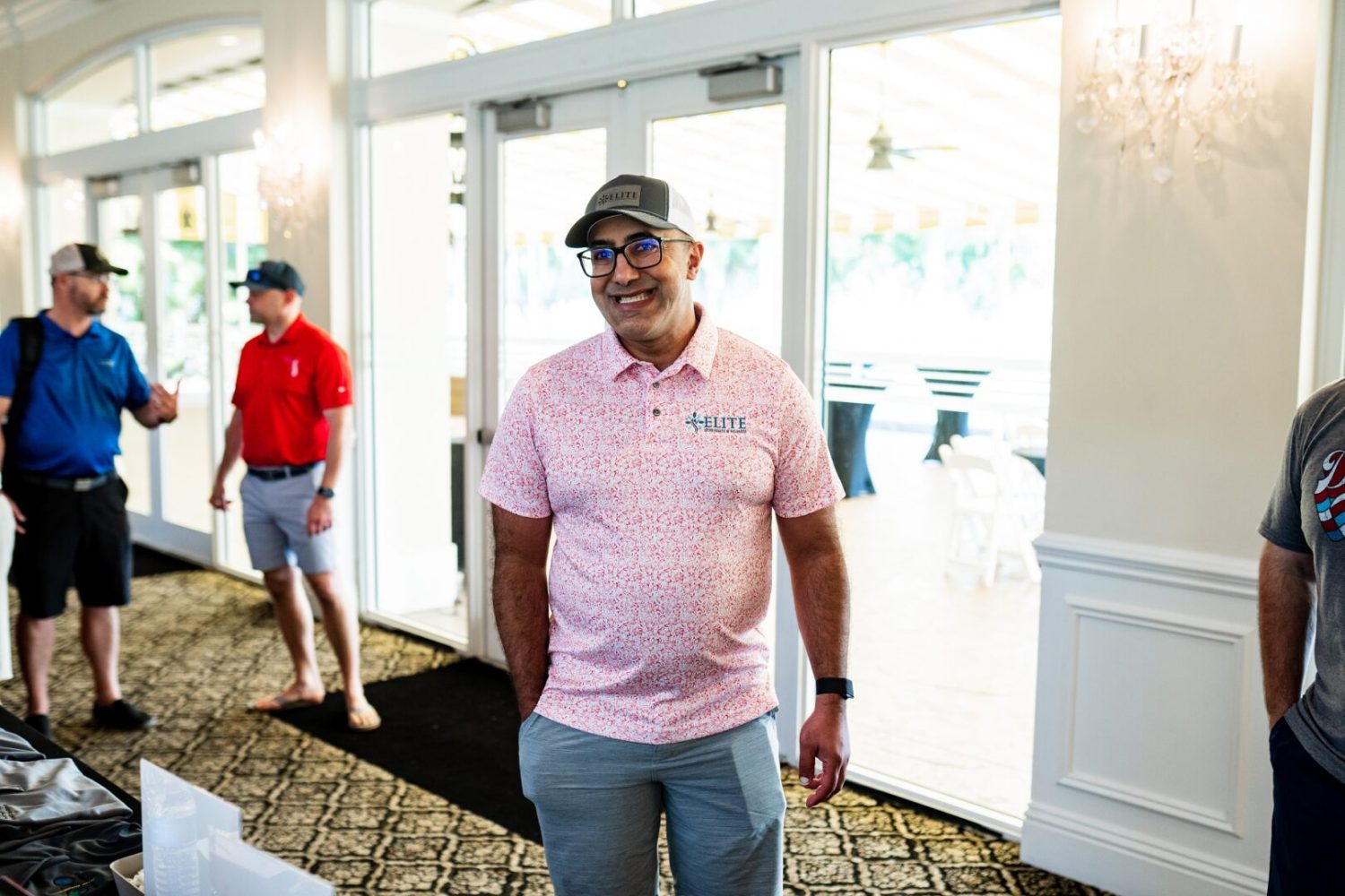 A man in pink shirt standing next to a door.