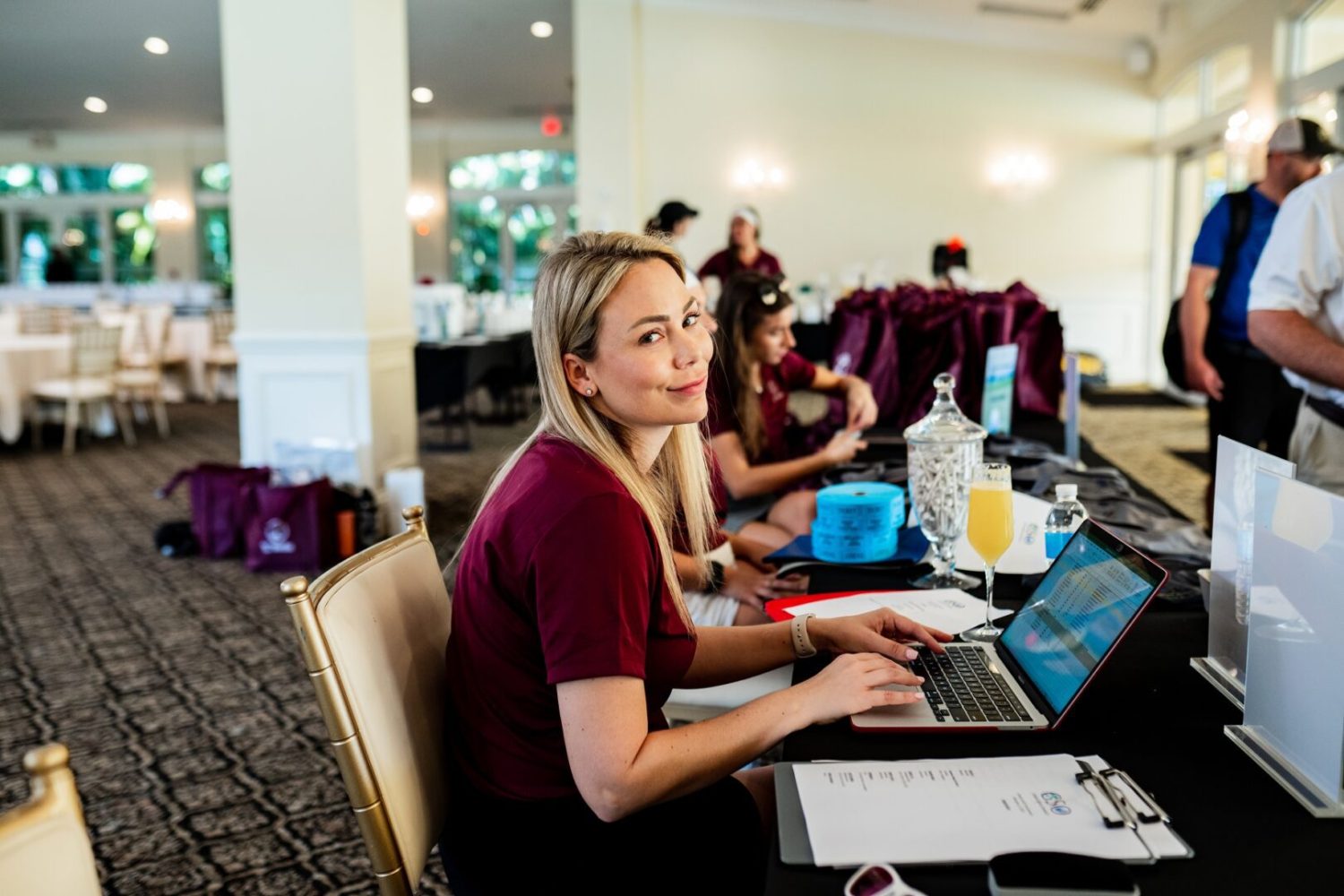 A woman sitting at a table with two laptops.