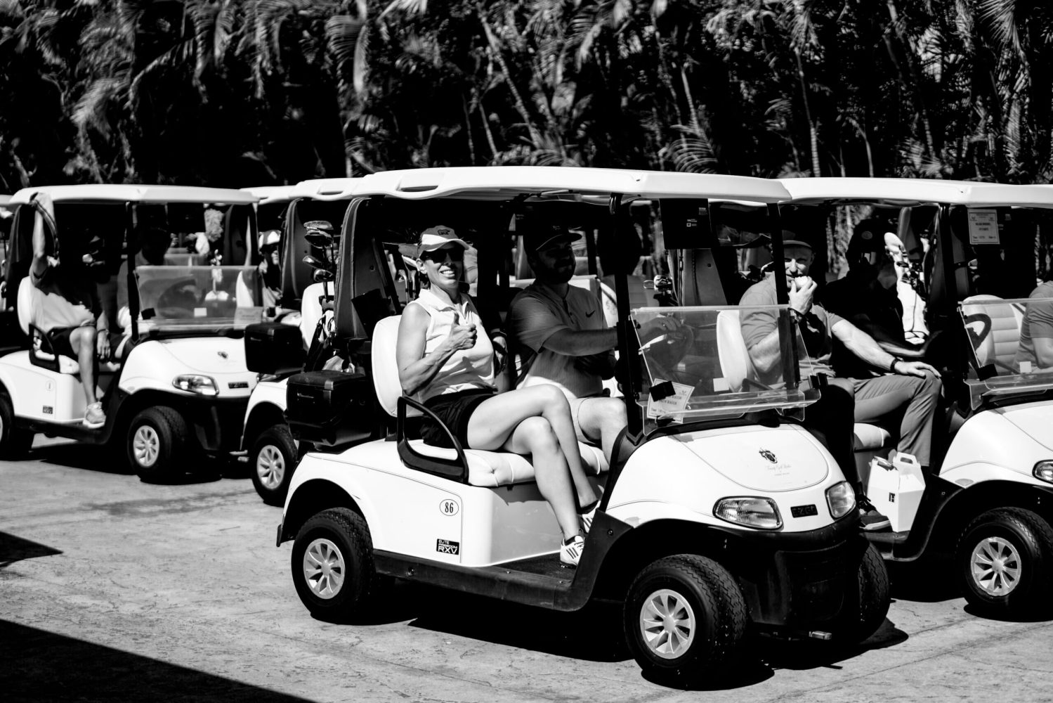 A group of people in golf carts on the road.