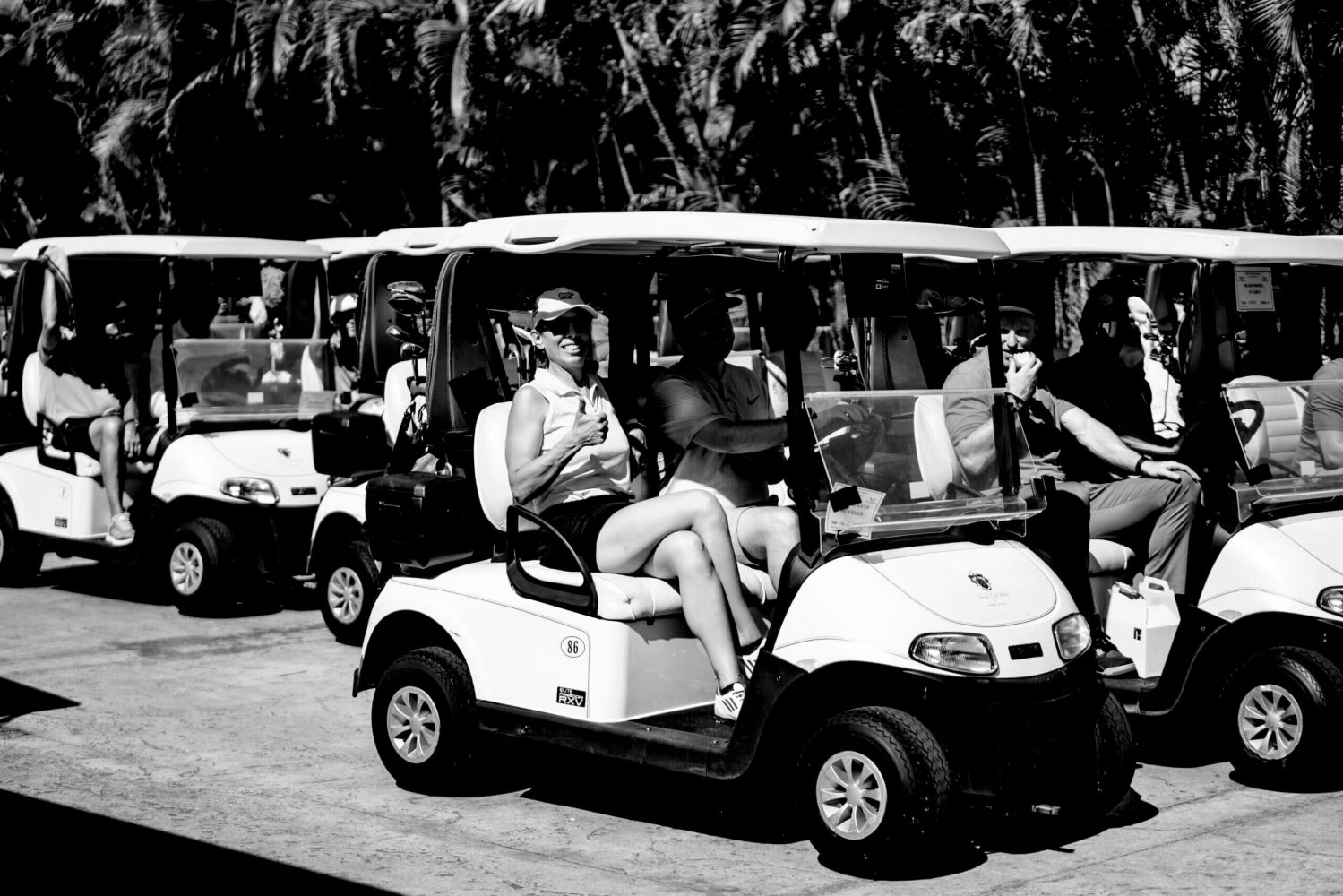 A group of people in golf carts on the road.