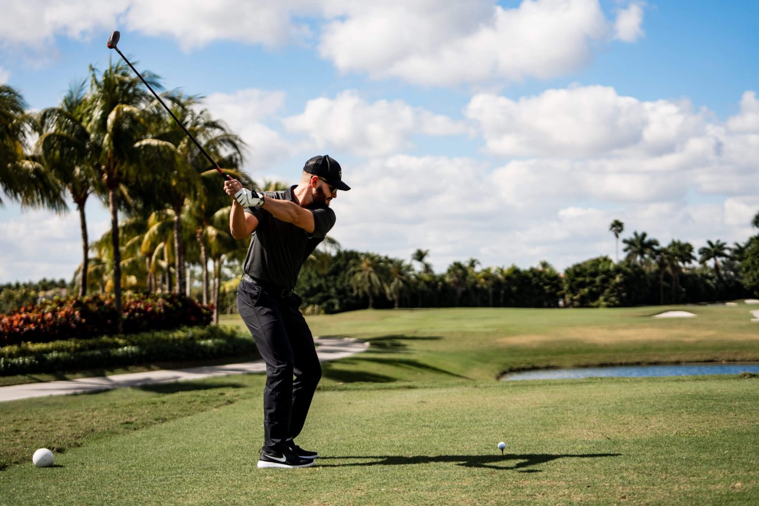 A man swinging at the golf ball on a course.