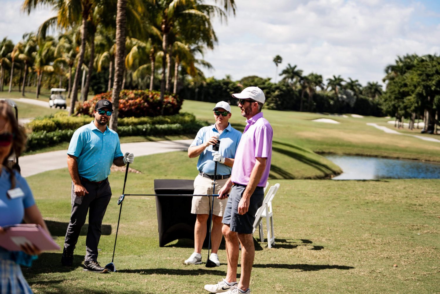 Three men standing on a golf course with trees in the background.
