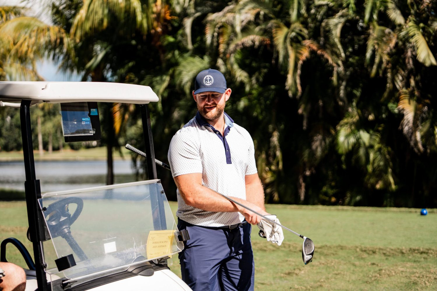A man holding a golf club next to a car.