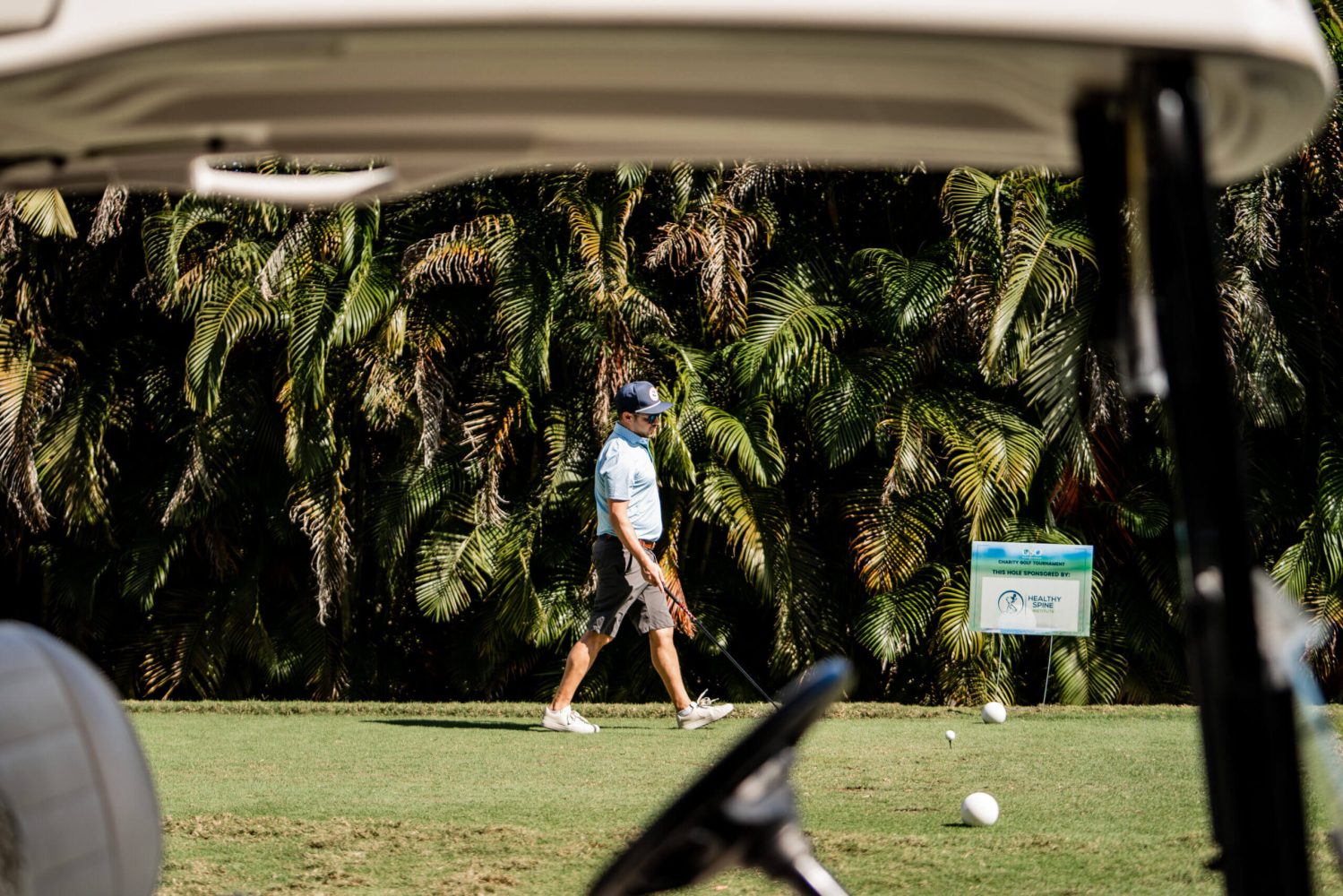 A man is walking on the grass while holding his golf club.