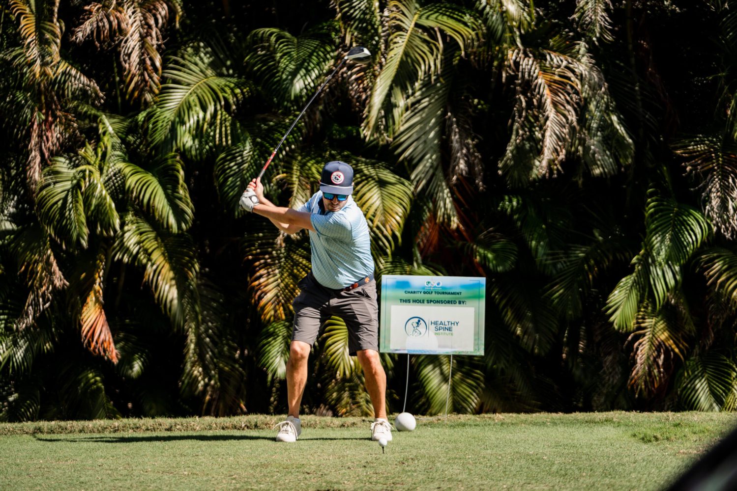A man swinging at a golf ball on the green.