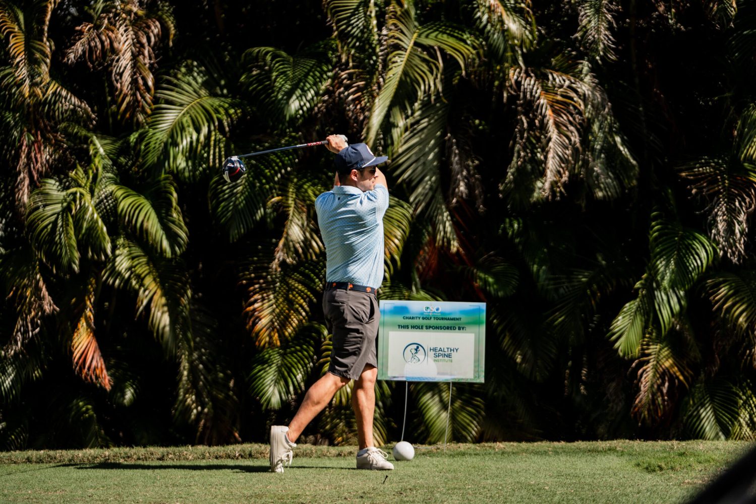 A man swinging at a golf ball on the green.