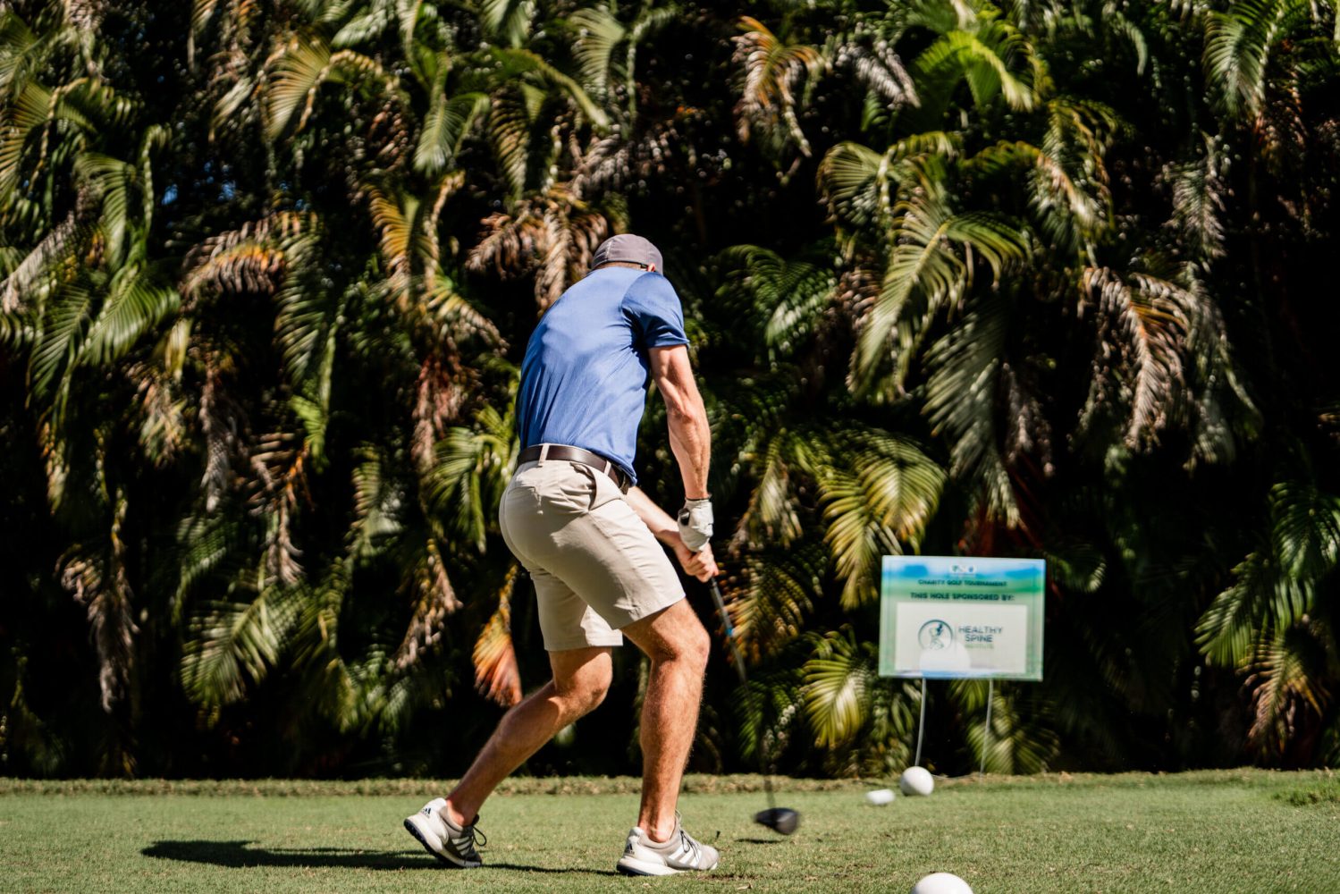 A man swinging at a golf ball on the green.