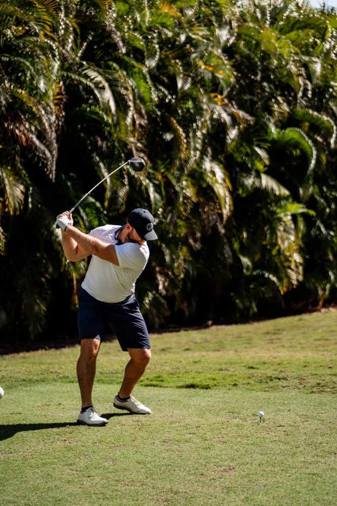 A man swinging at a golf ball on the green.