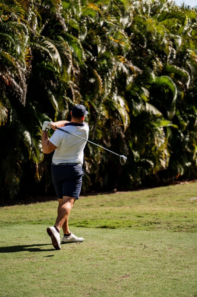 A man swinging at a golf ball on the green.