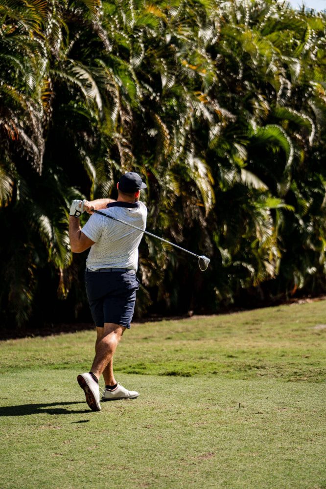 A man swinging at a golf ball on the green.