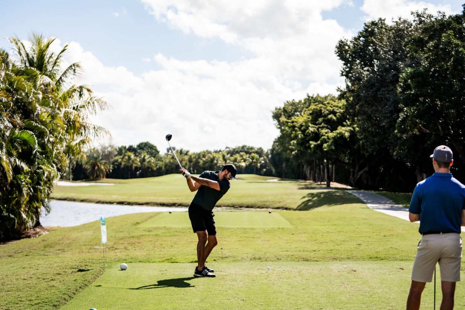 A man swinging at a golf ball on the green.