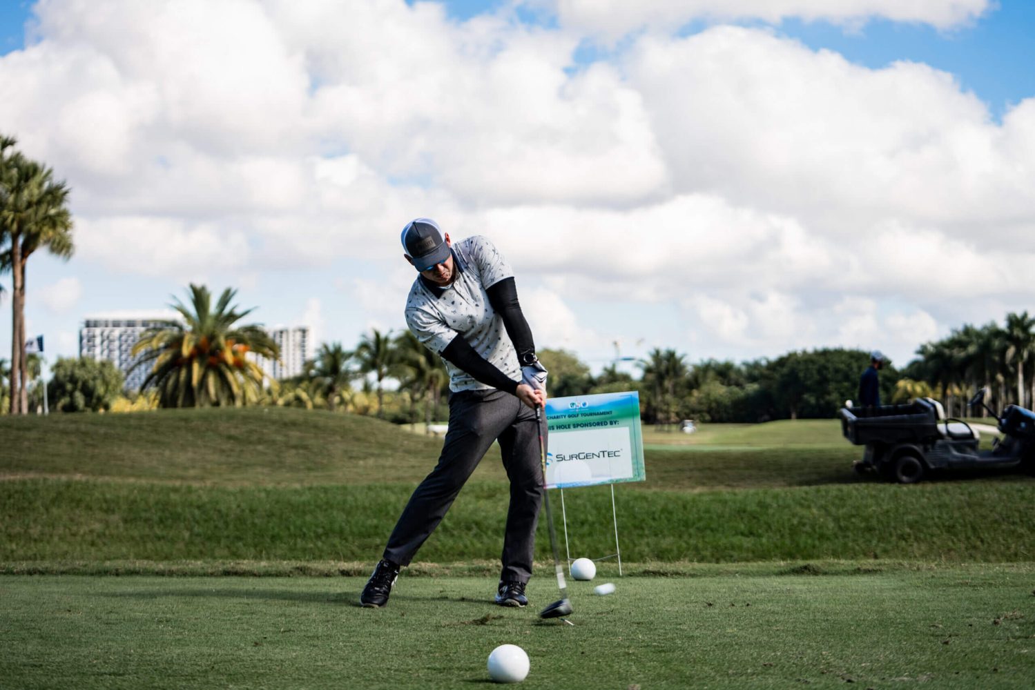 A man swinging at a golf ball on the green.