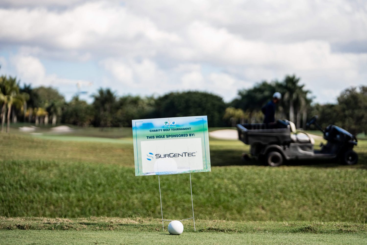 A golf ball on the green with a sign in front of it.