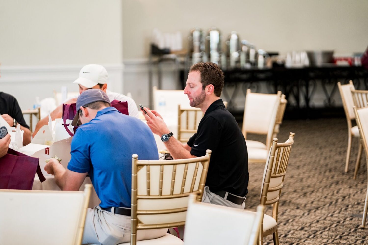 A group of men sitting at tables in front of drinks.