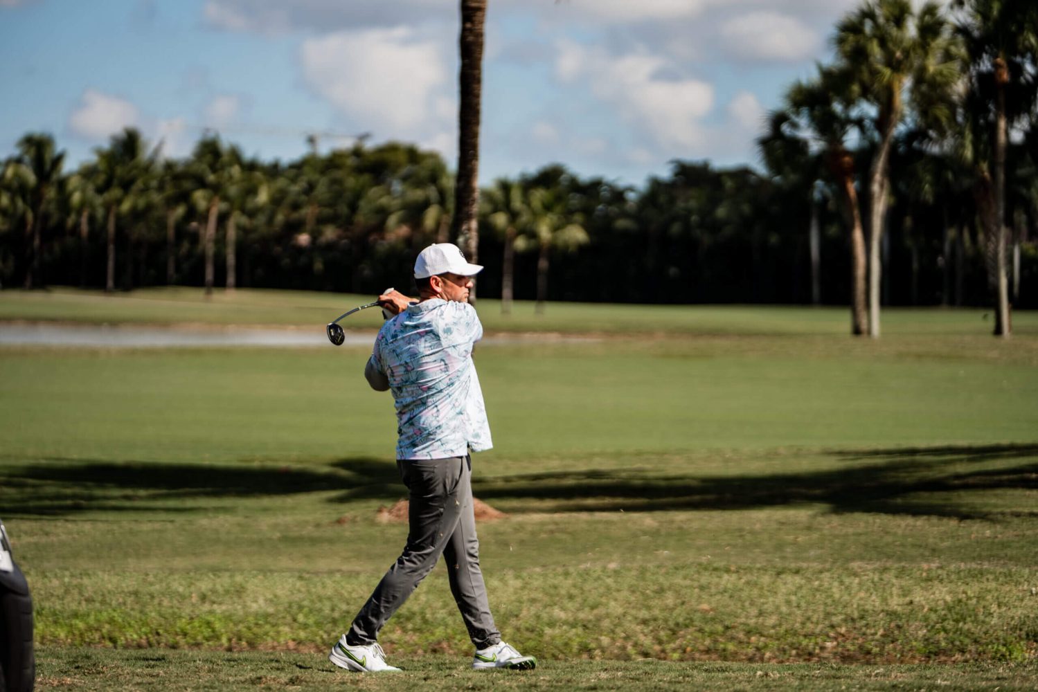 A man holding onto a golf club while standing on the grass.