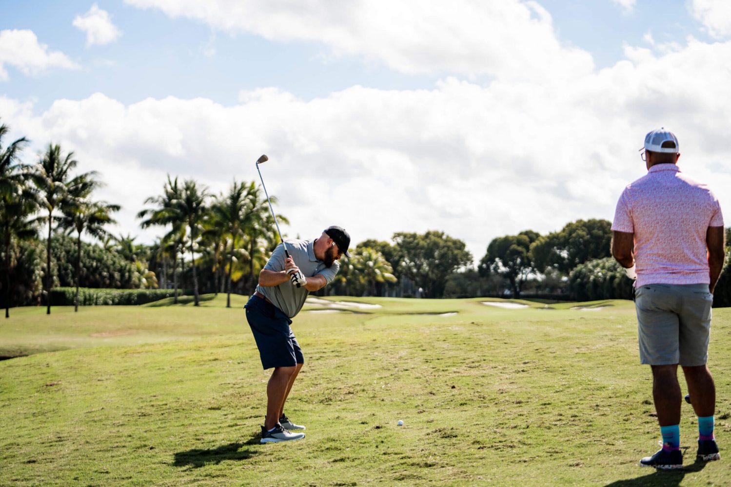 A man swinging at a golf ball on the green.