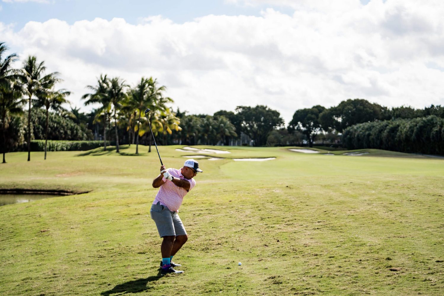A man swinging at the golf ball on a course.