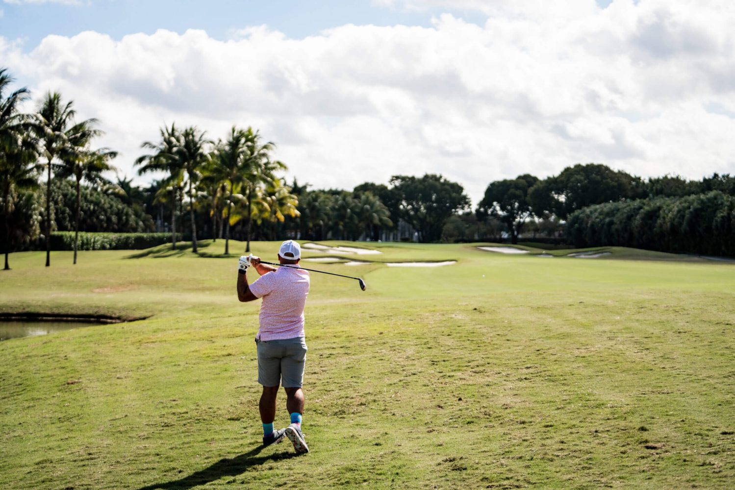 A man in pink shirt holding a golf club.