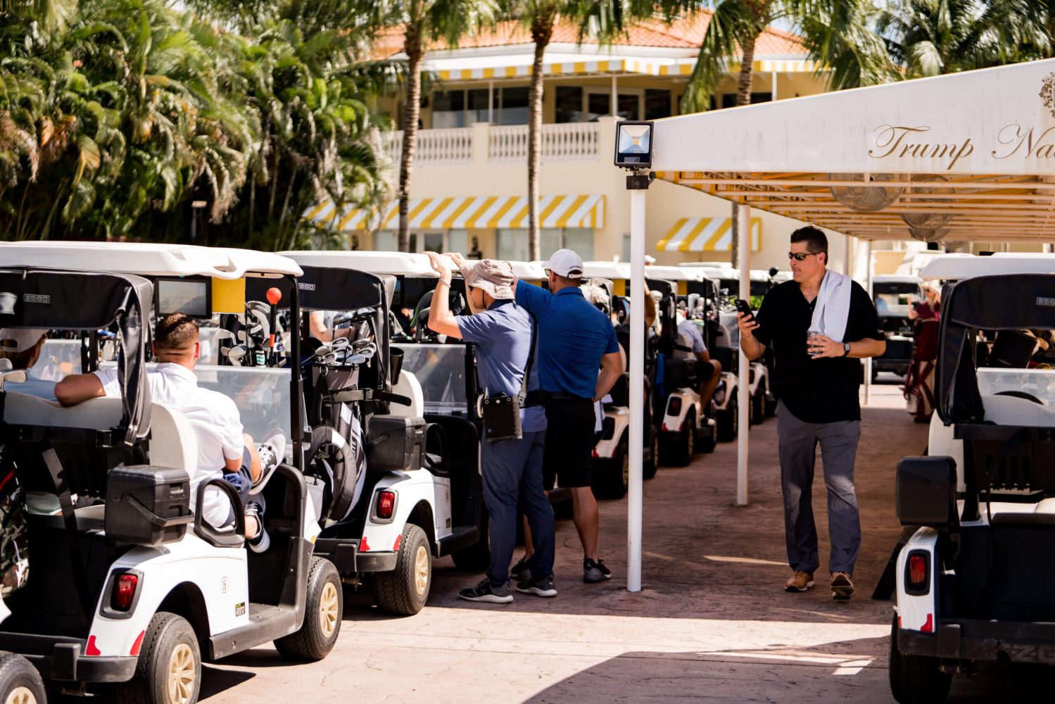 A group of people standing around parked golf carts.