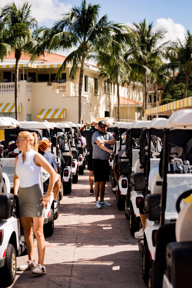 A group of people standing around parked golf carts.