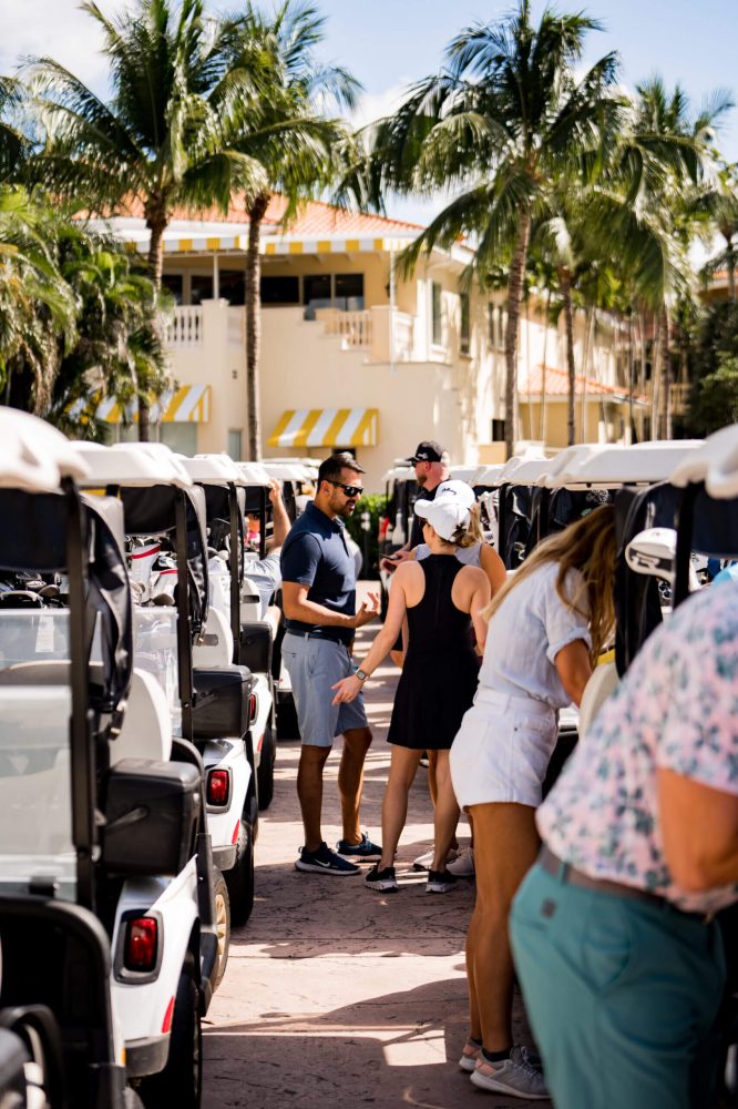 A group of people standing around parked golf carts.