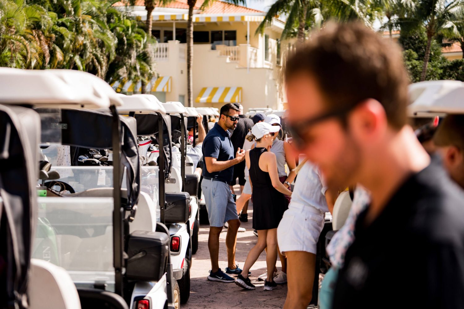 A group of people standing around parked golf carts.