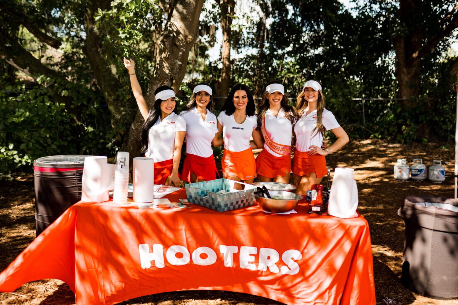 A group of hooters girls standing at the table.
