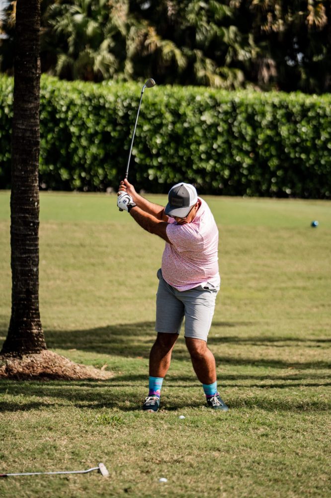 A man swinging at a golf ball on the green.