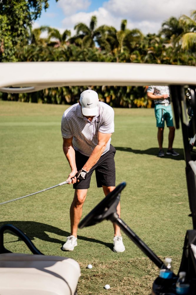 A man holding onto the golf club while standing on a green.