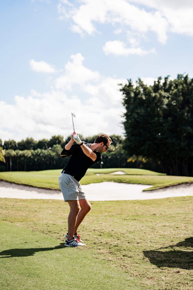 A man swinging at the golf ball on a course.