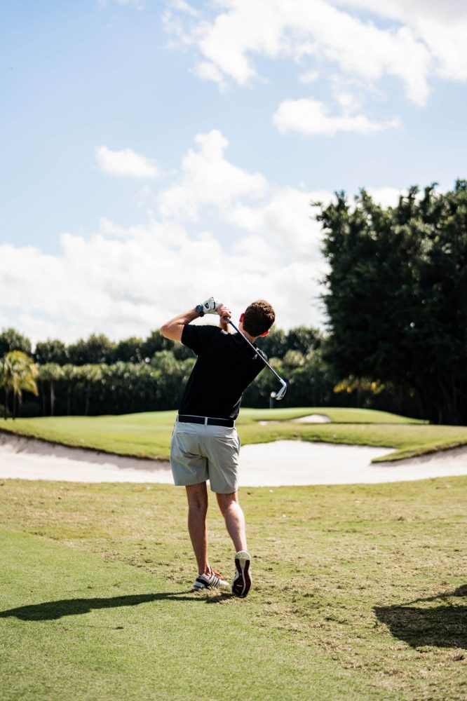 A man is swinging at the golf course
