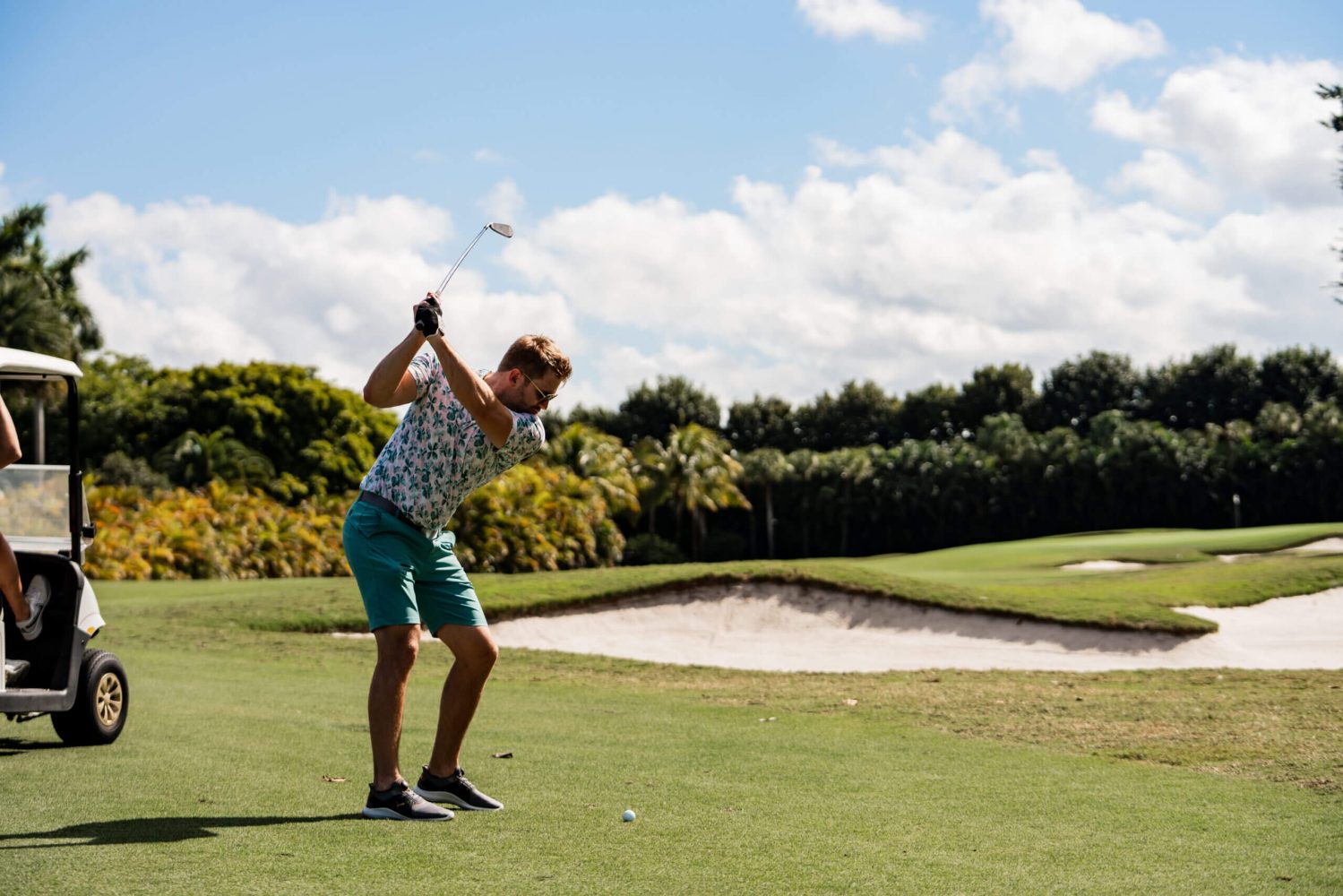 A man holding onto the golf club while standing on a green.