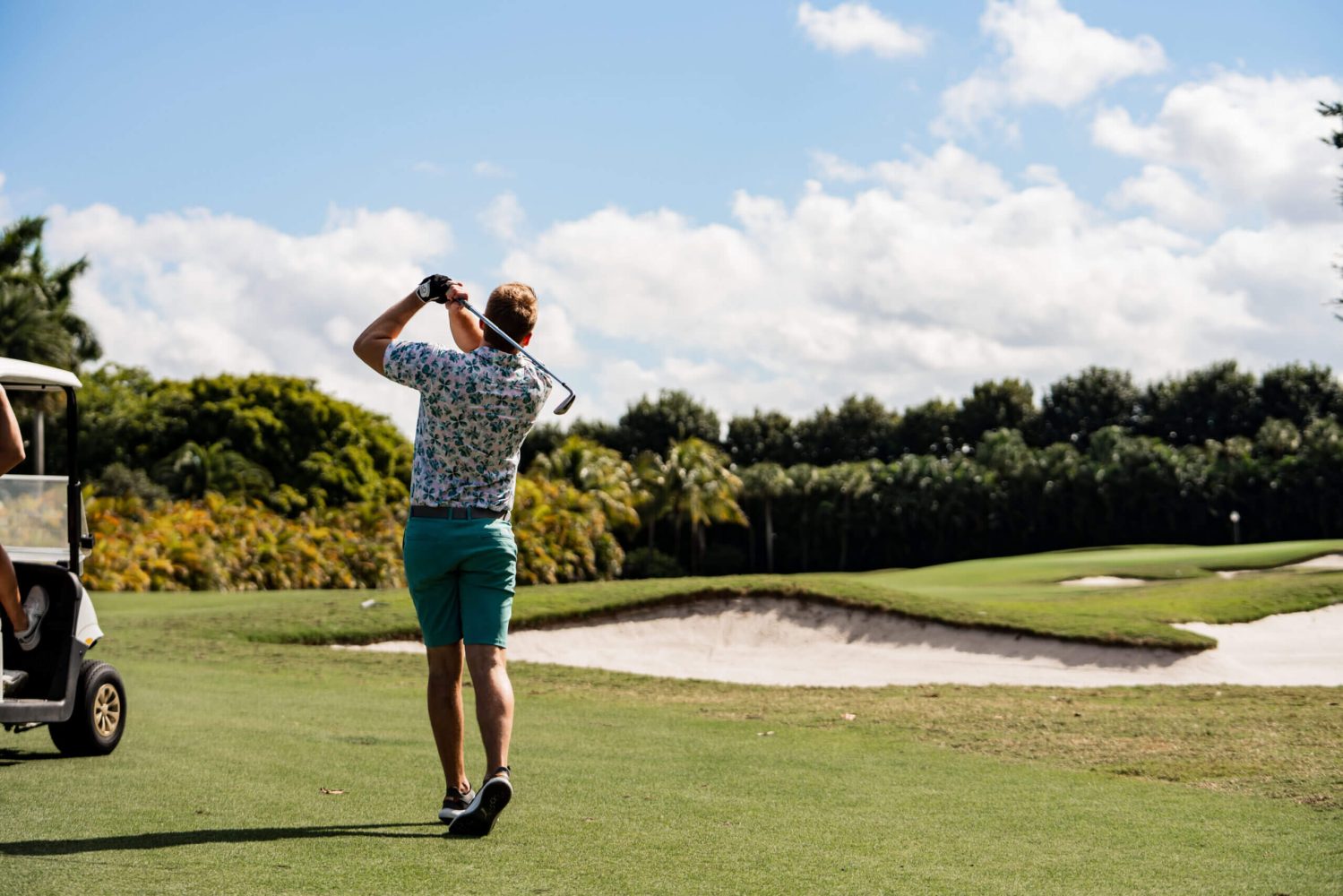 A man holding onto his golf club while standing on the course.