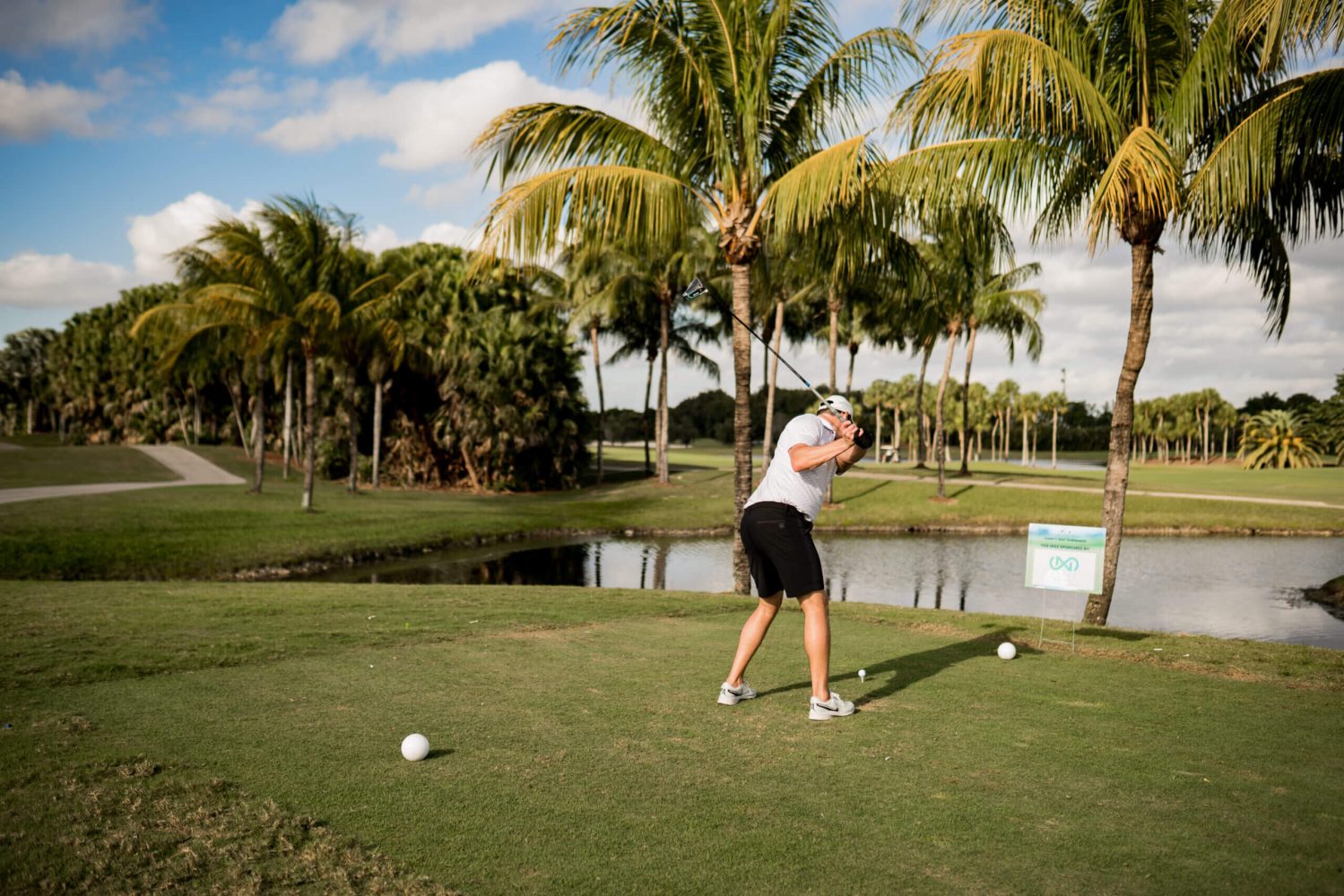 A man swinging at a golf ball on the green.