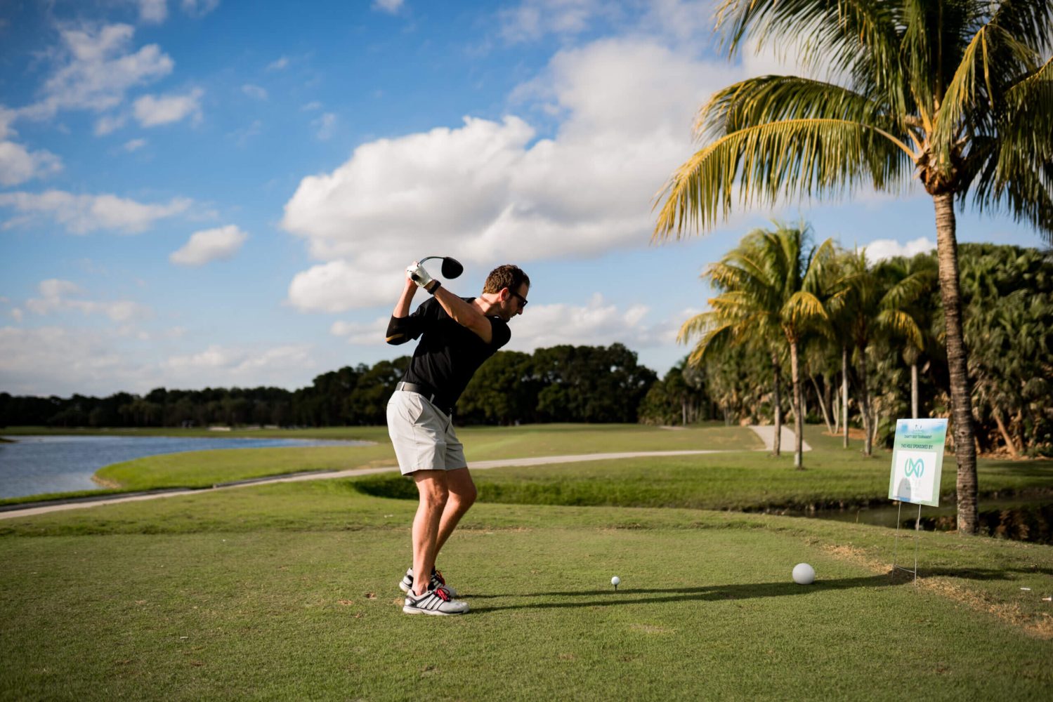 A man swinging at a golf ball on the green.