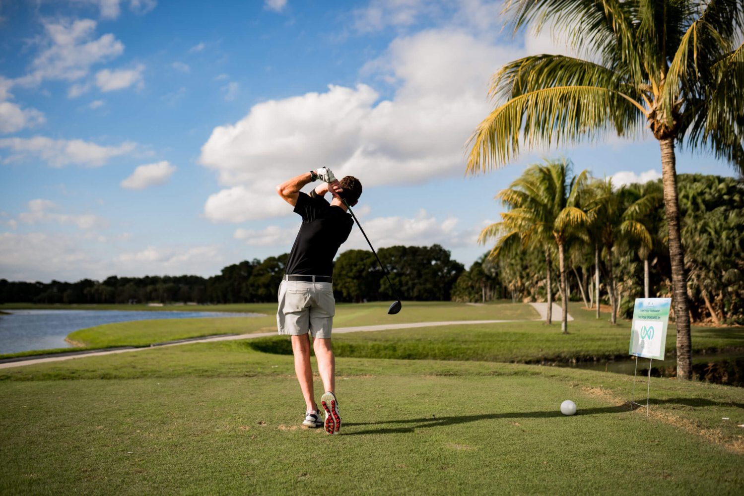 A person swinging at a golf ball on the green
