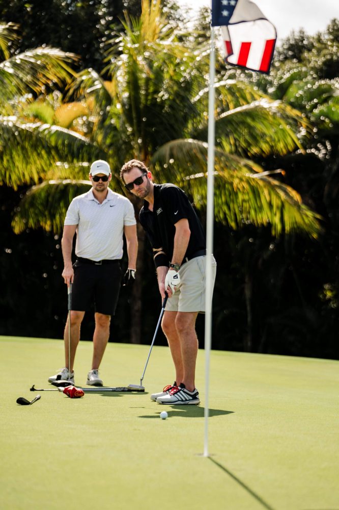 Two men standing on a golf course with their clubs.