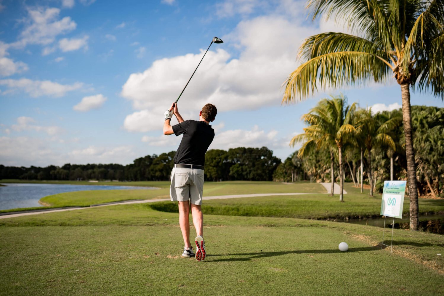 A man is swinging at the golf ball.