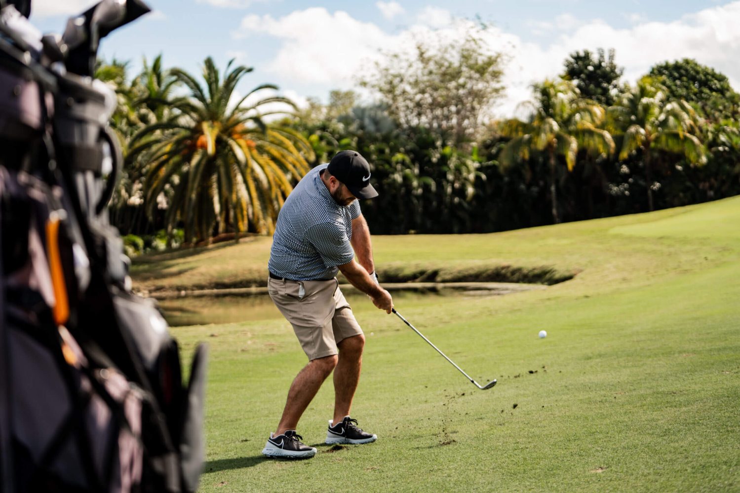 A man swinging at the golf ball on a course.
