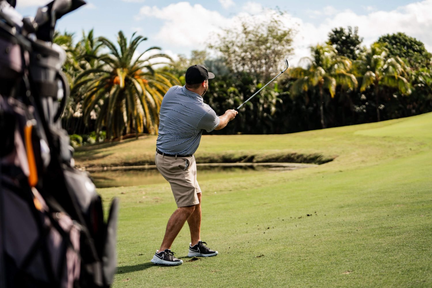 A man swinging at a golf ball on the green.
