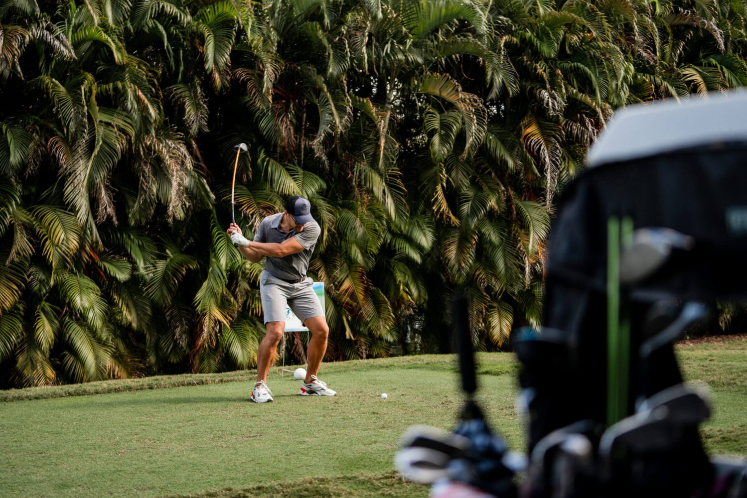 A man swinging at a golf ball on the green.