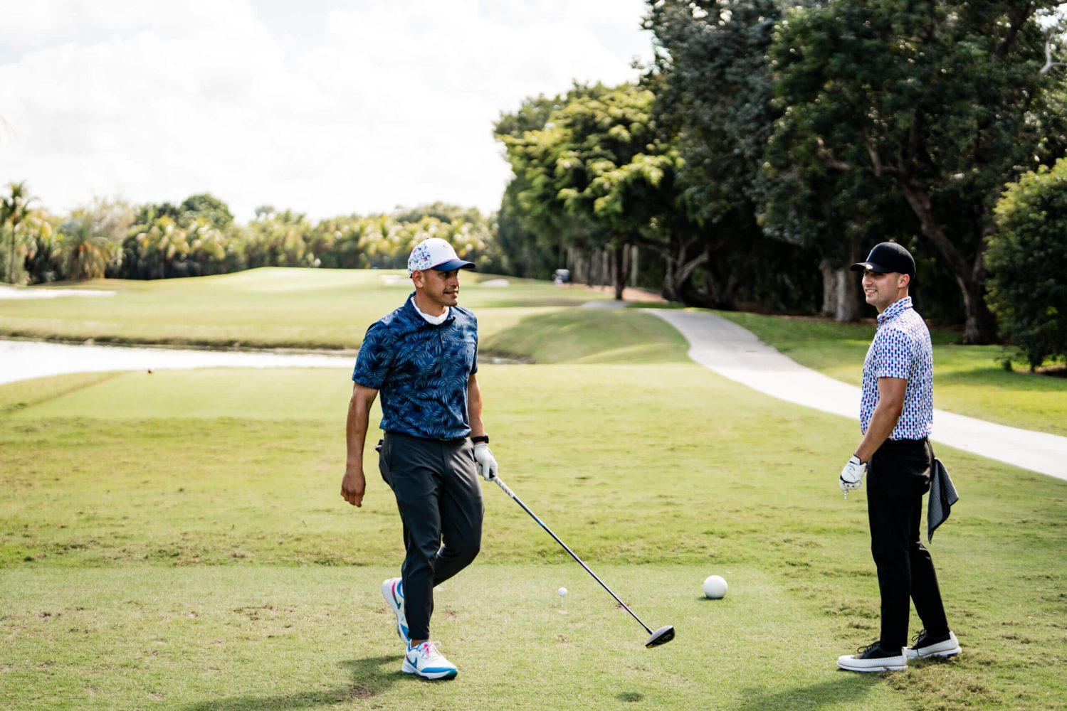 Two men standing on a golf course with their clubs.