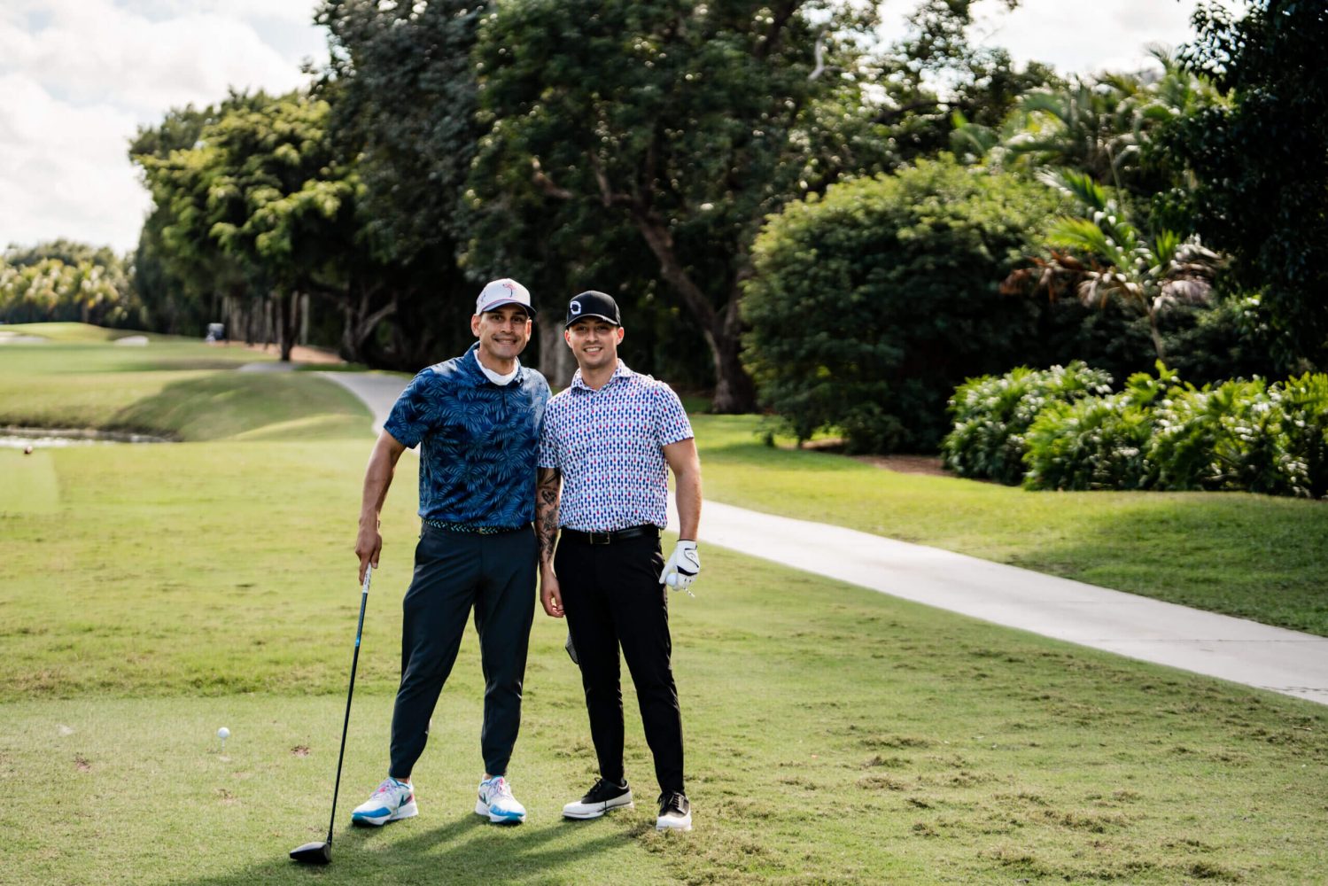 Two men standing on a golf course holding onto their clubs.