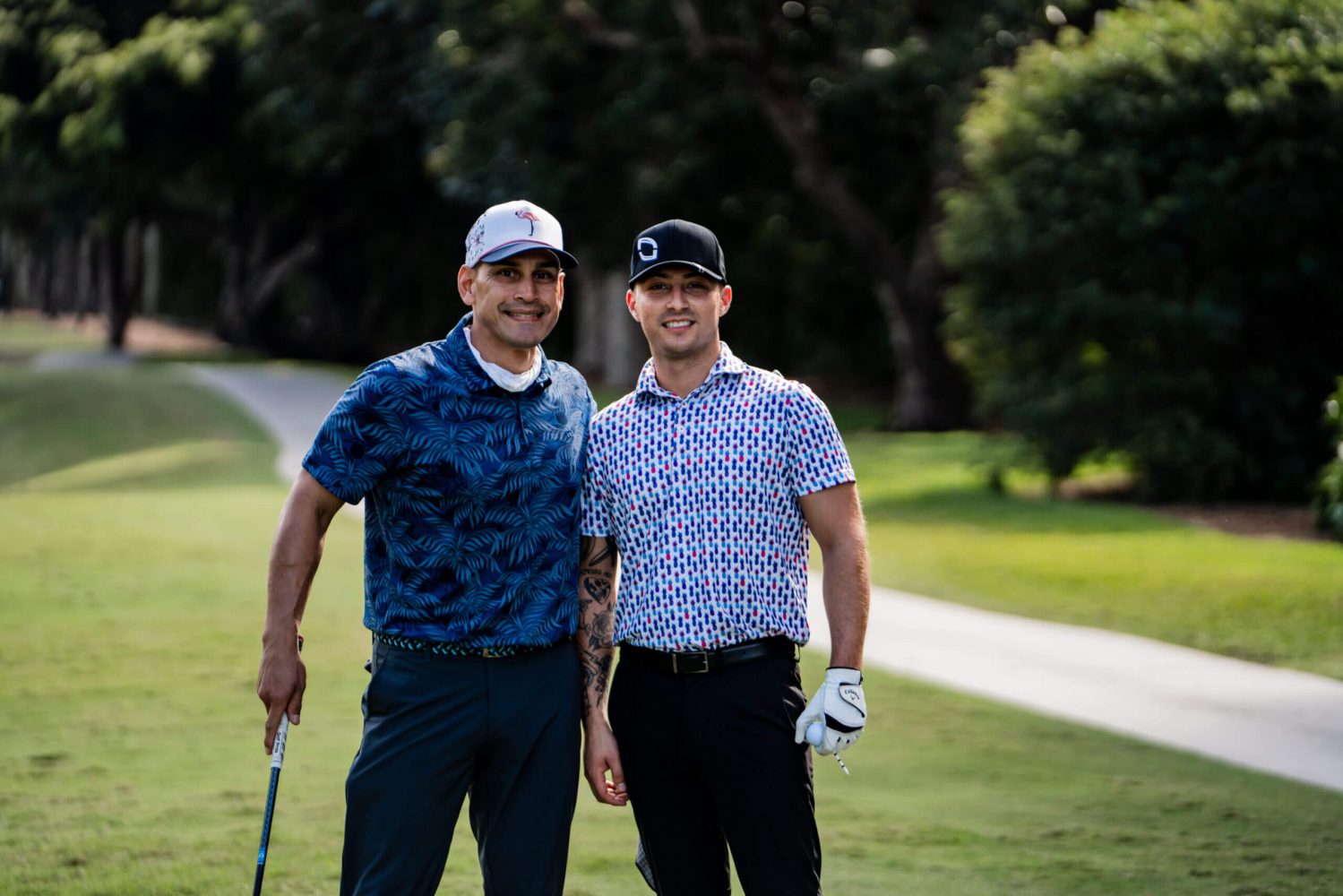 Two men standing on a golf course holding their clubs.
