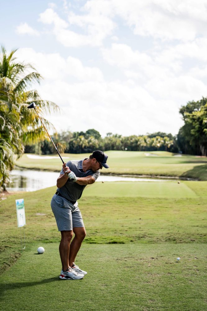 A man swinging at a golf ball on the course.