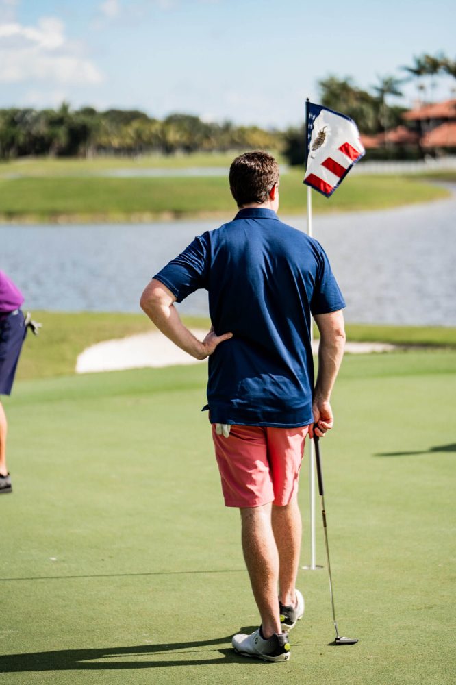 A man standing on top of a golf course holding a flag.
