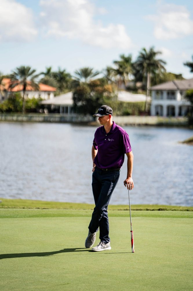 A man holding a golf club on top of a green.