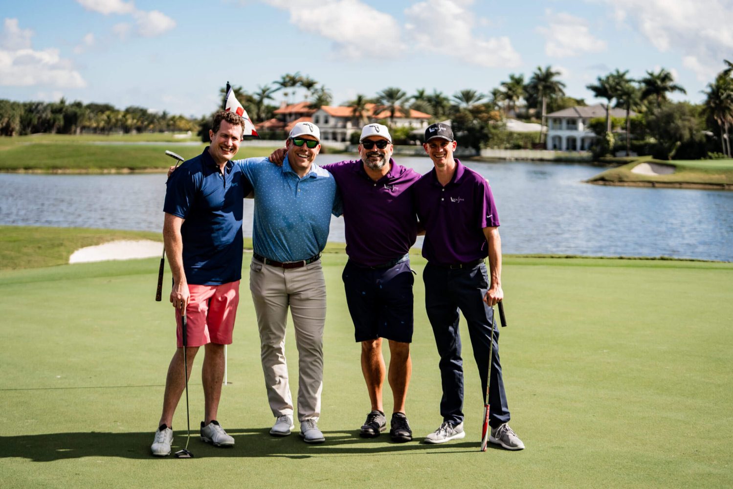 Four men standing on a golf course holding their clubs.