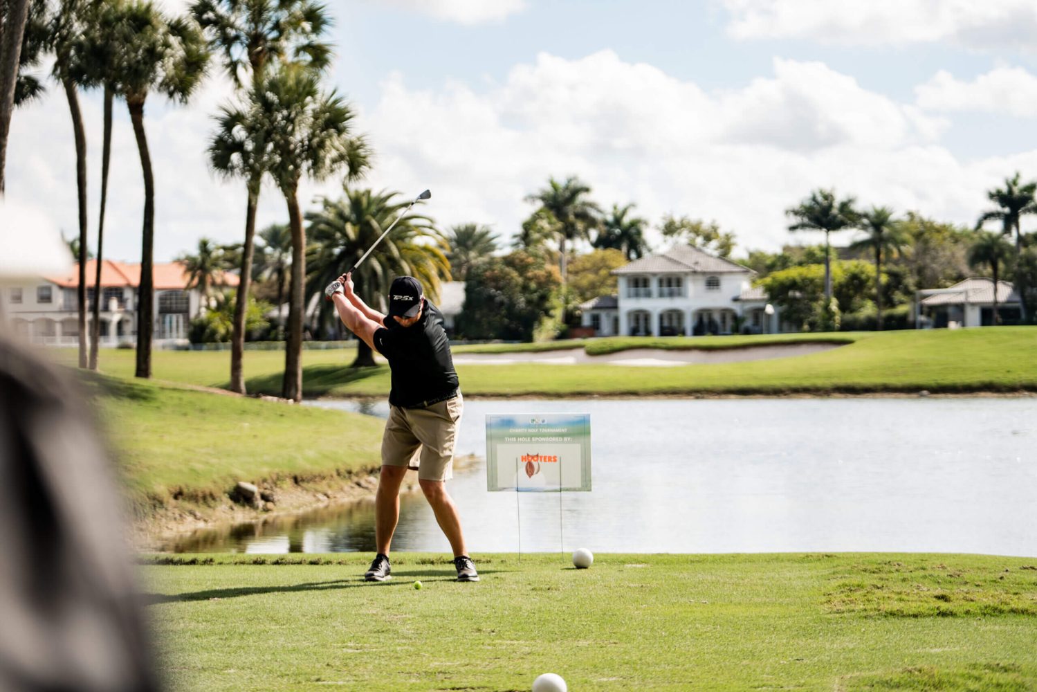 A man swinging at a golf ball on the course.