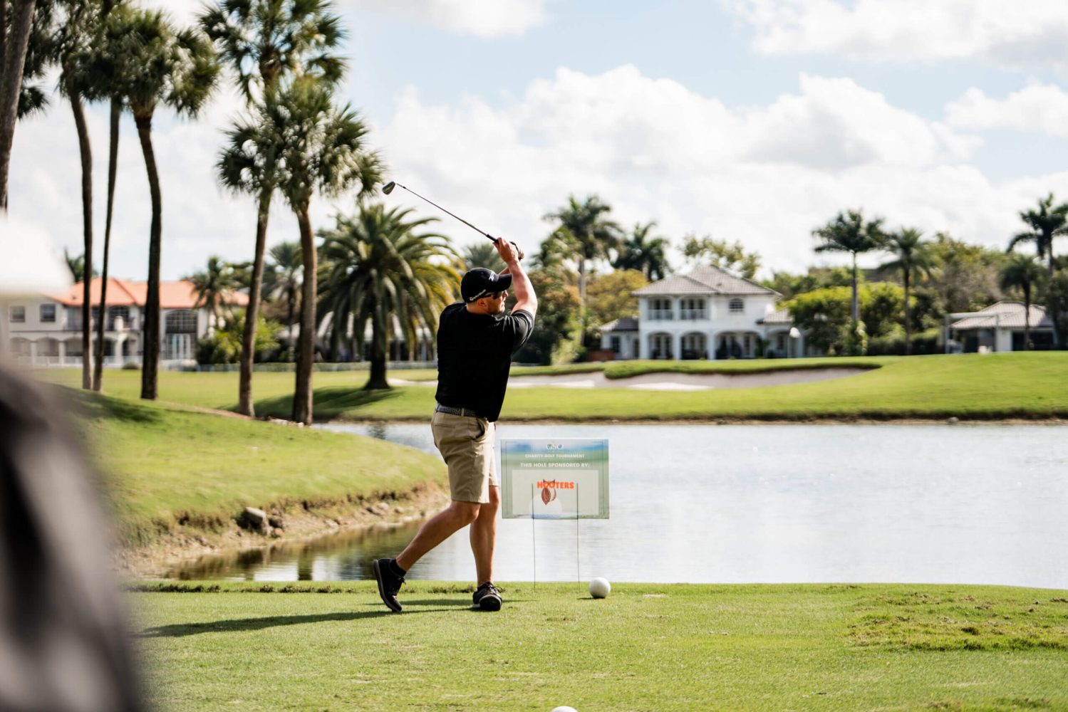 A man swinging at a golf ball on the course.